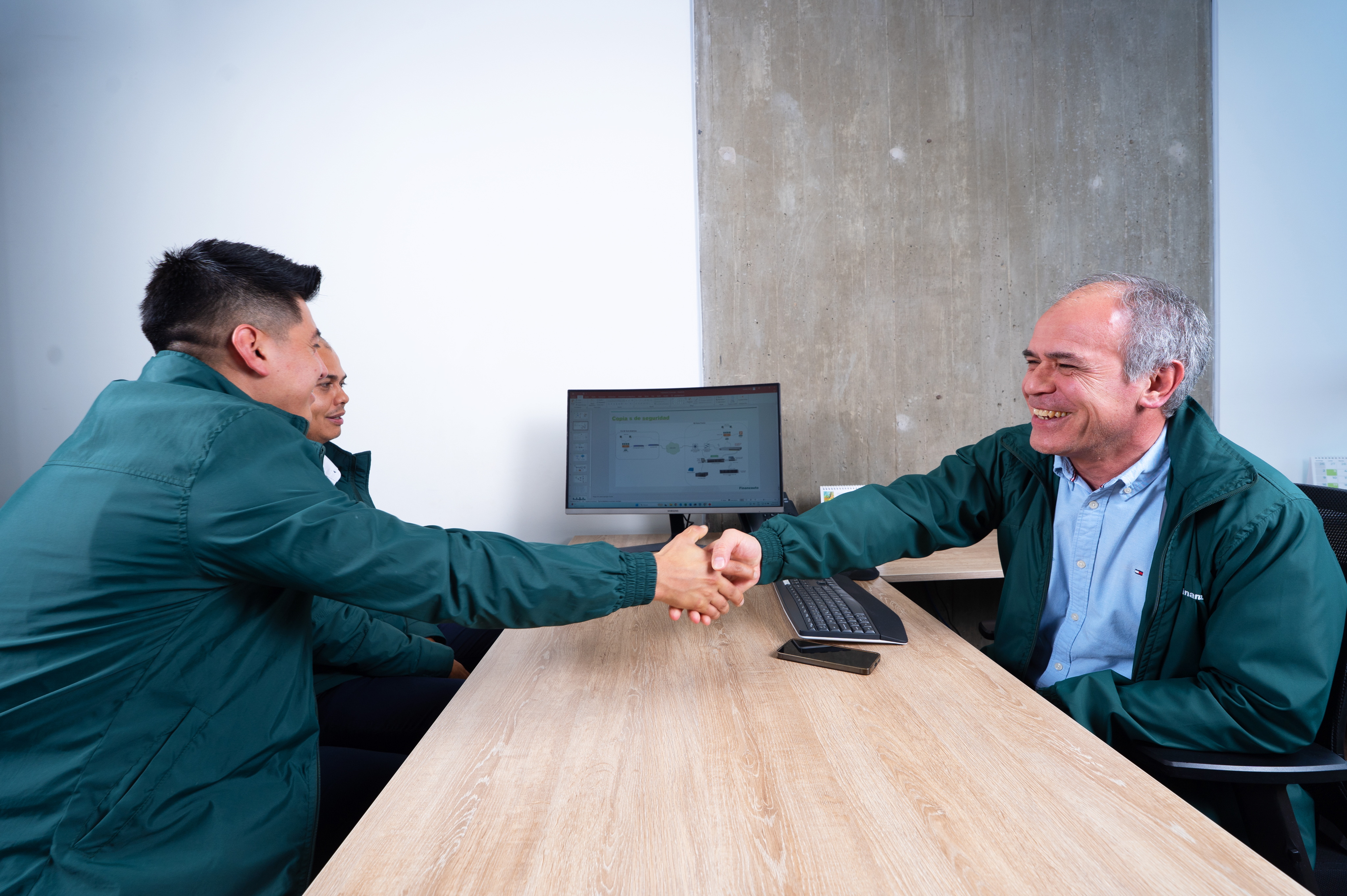 Empleados sonriendo mientras se saludan con un apretón de manos.